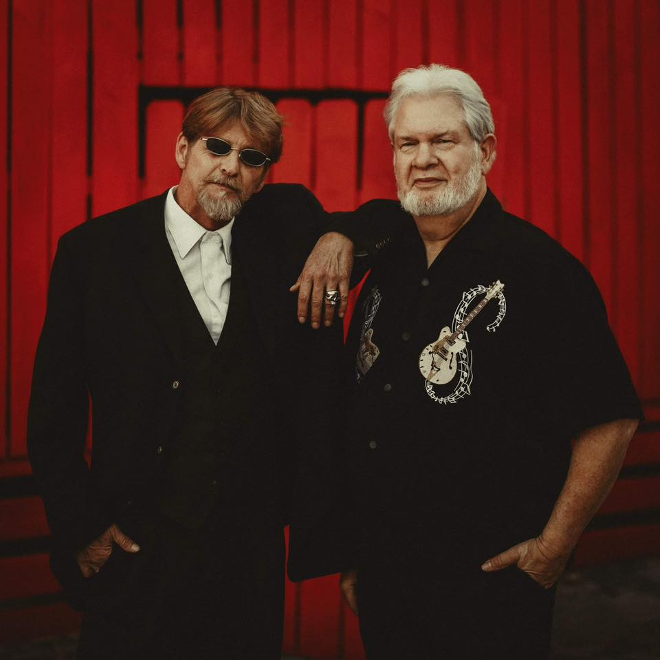 John Paul Drum and Bill Dye standing against a red background